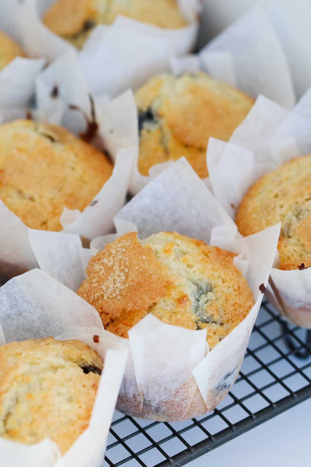 Muffins in white paper liners on a wire cooling rack.