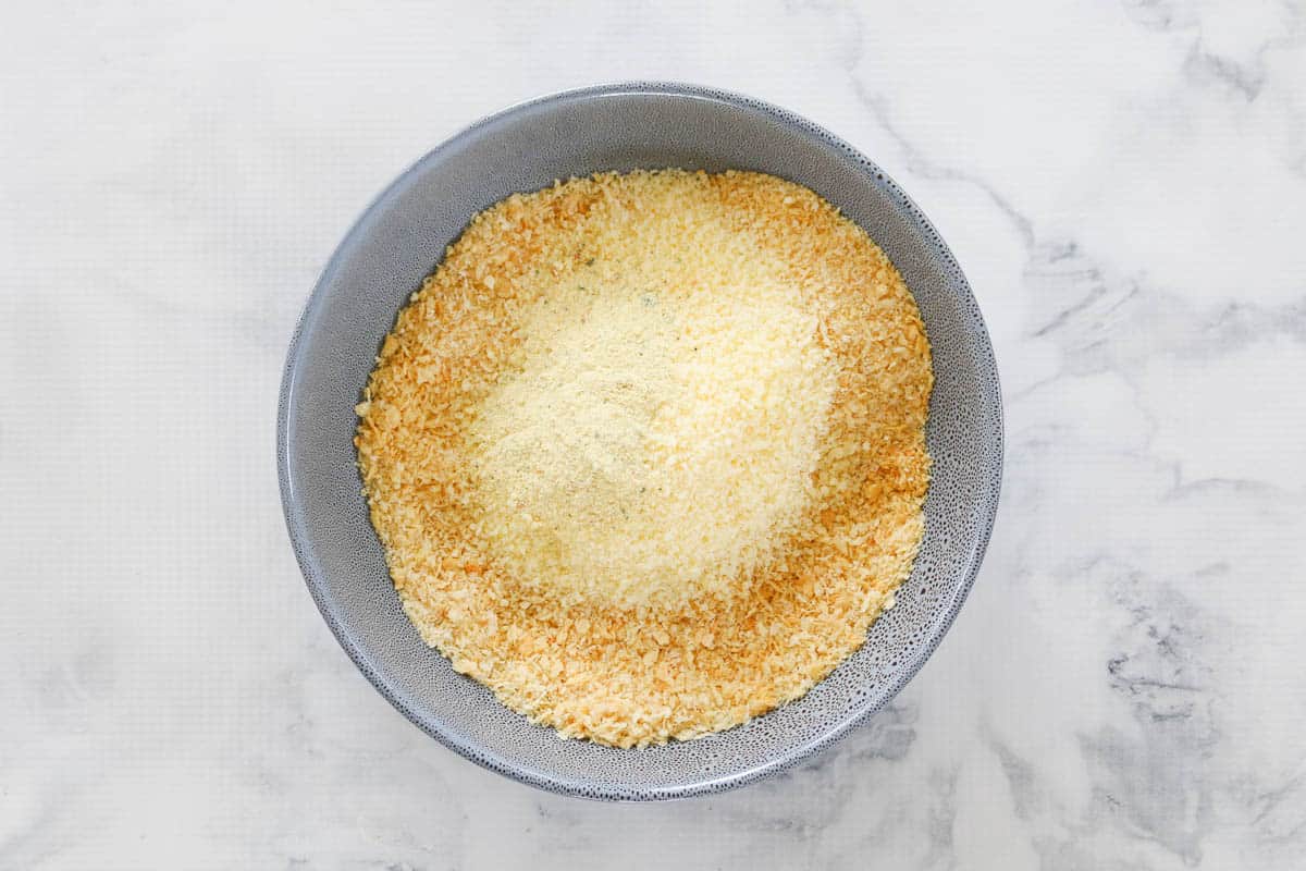 Grated parmesan cheese on top of a bowl of golden baked panko crumbs.