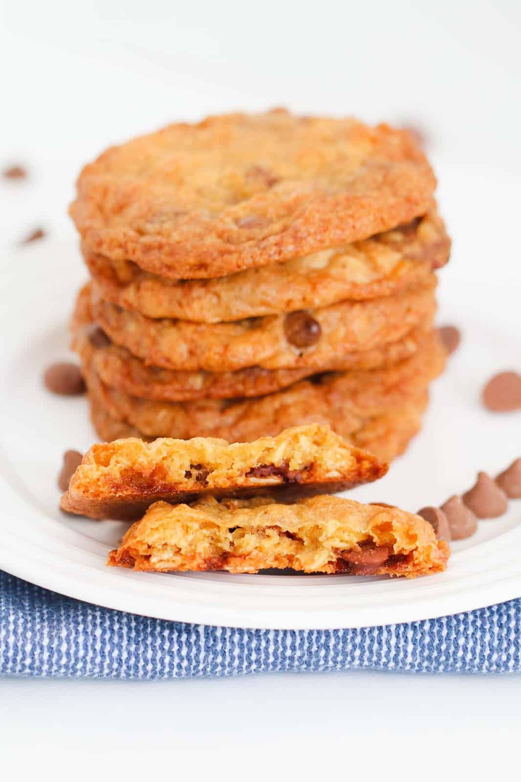 A stack of chocolate chip cookies with a cookie broken in half at the front.