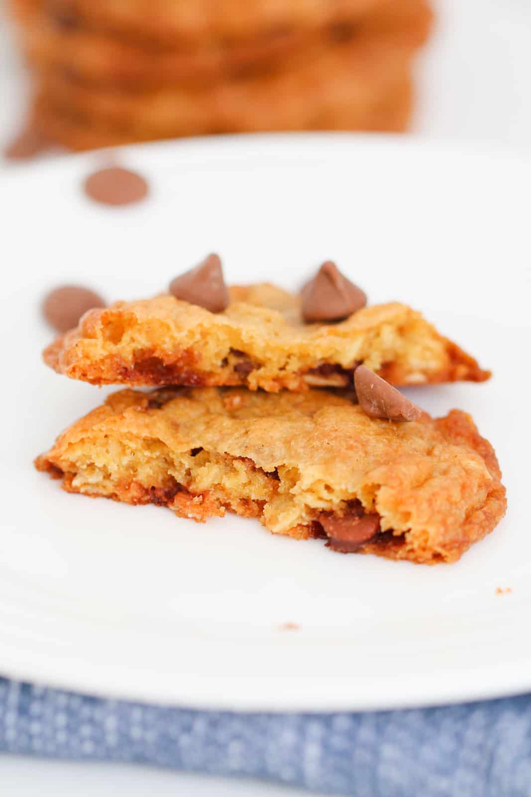 A oat cookie with chocolate chips broken in half on a white plate.