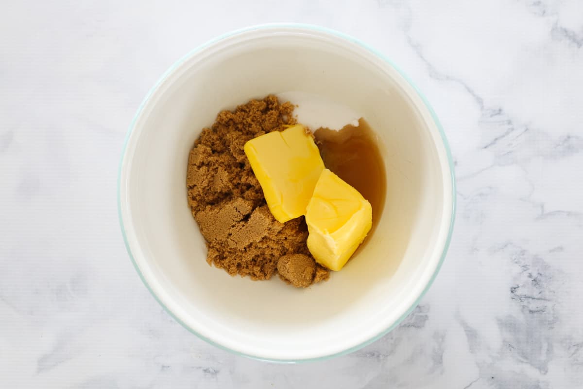 Butter, brown sugar and caster sugar in a white mixing bowl.