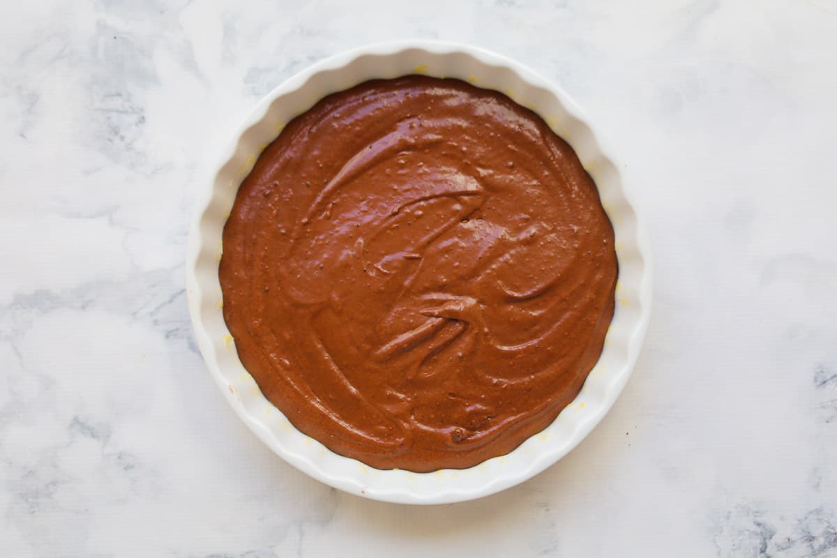 Chocolate pudding mixture in a greased round baking dish.