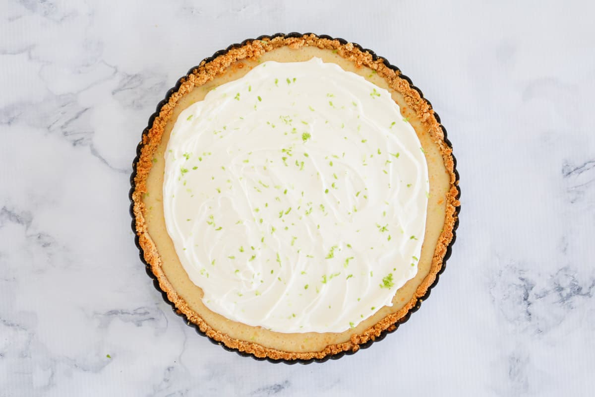 Whipped cream and lime zest on top of a baked citrus flavoured pie