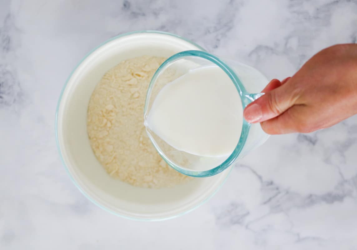 Milk being poured into a bowl of flour and butter crumbs.