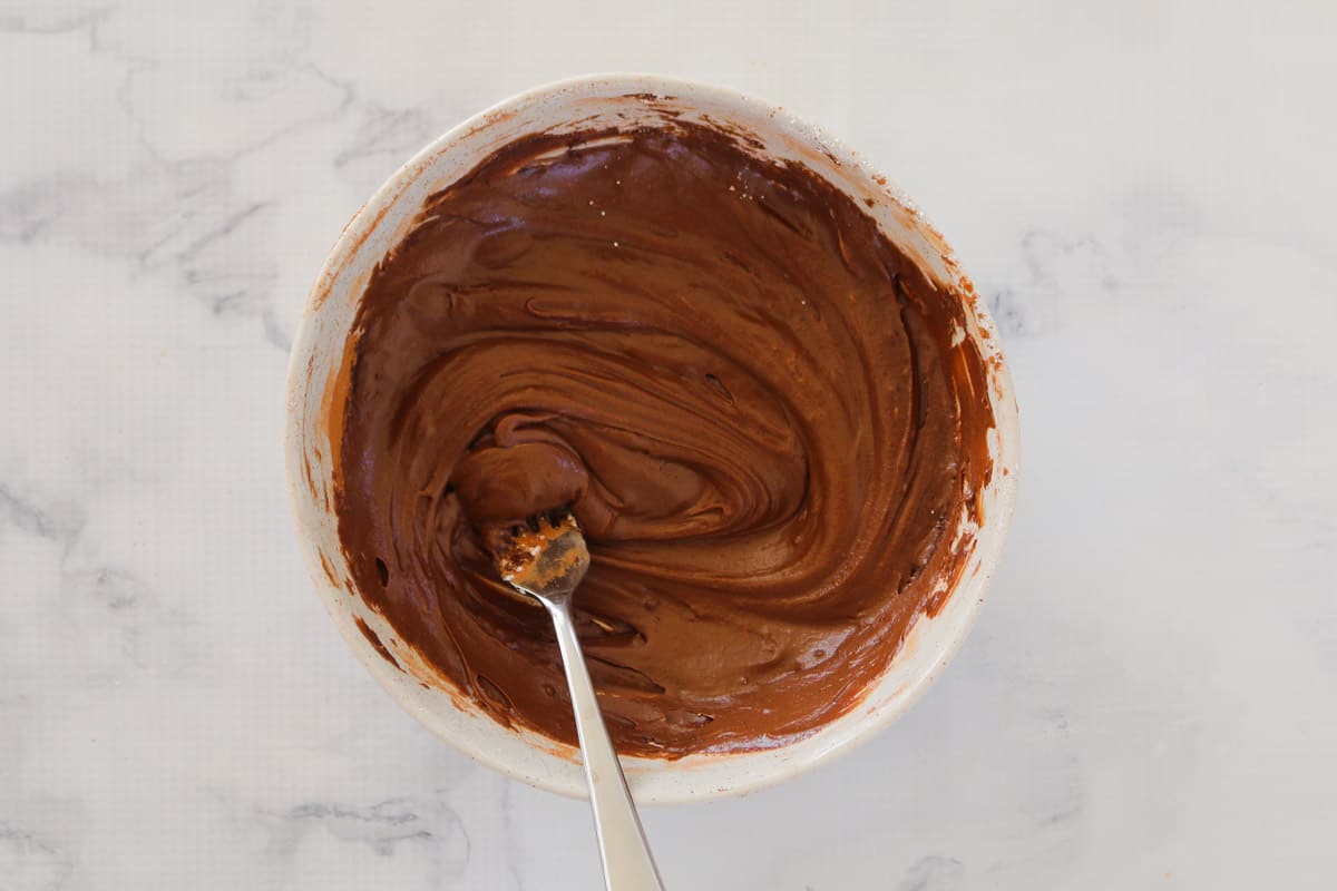 Chocolate icing in a white mixing bowl.
