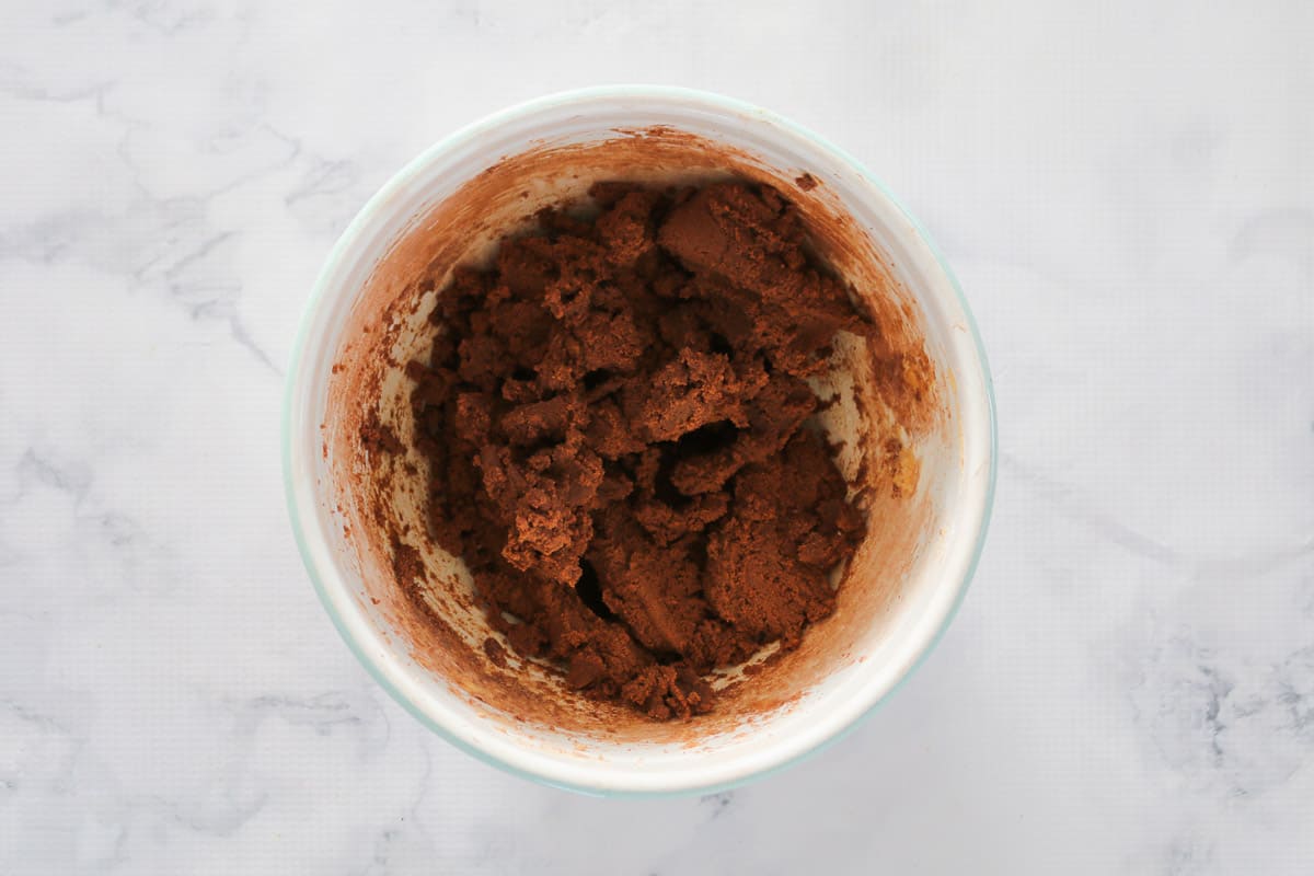 Chocolate biscuit mixture in a white mixing bowl.
