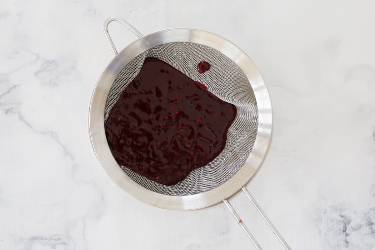 Blackberry puree in a silver metal strainer.