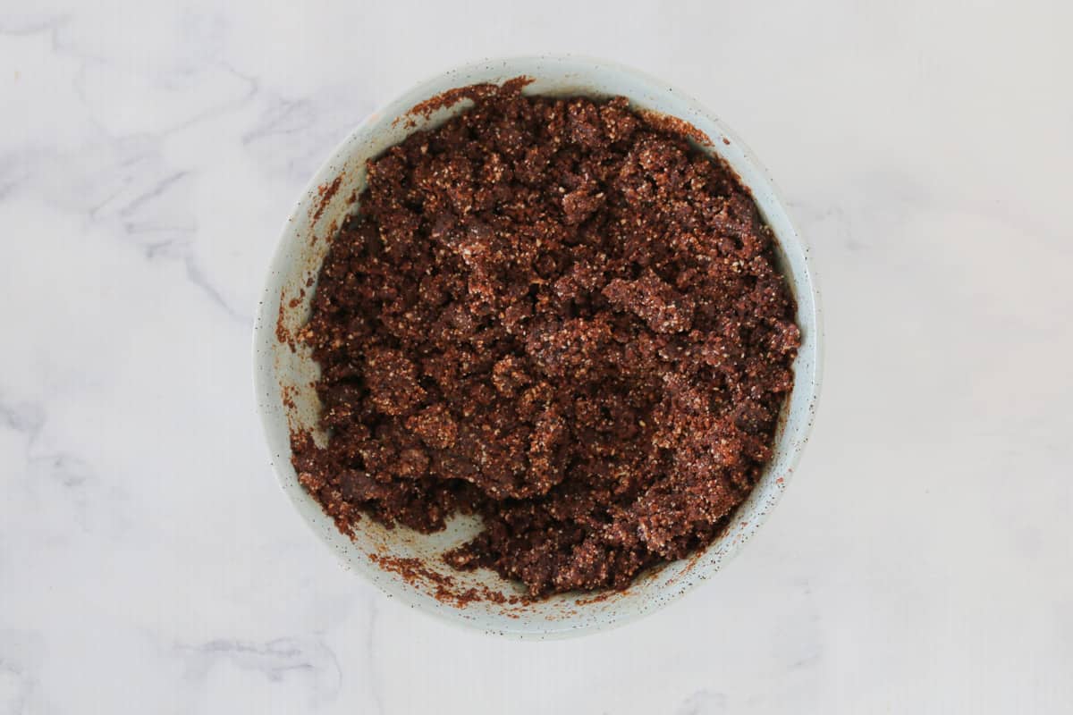 Crushed biscuits, almond meal and melted butter mixed together in a bowl to make chocolate crumbs. 