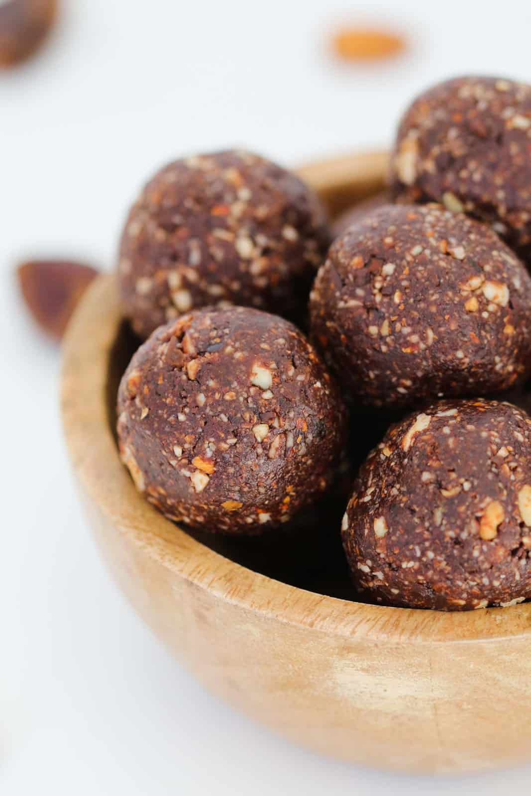 Date, almond and chocolate protein balls in a wooden bowl.