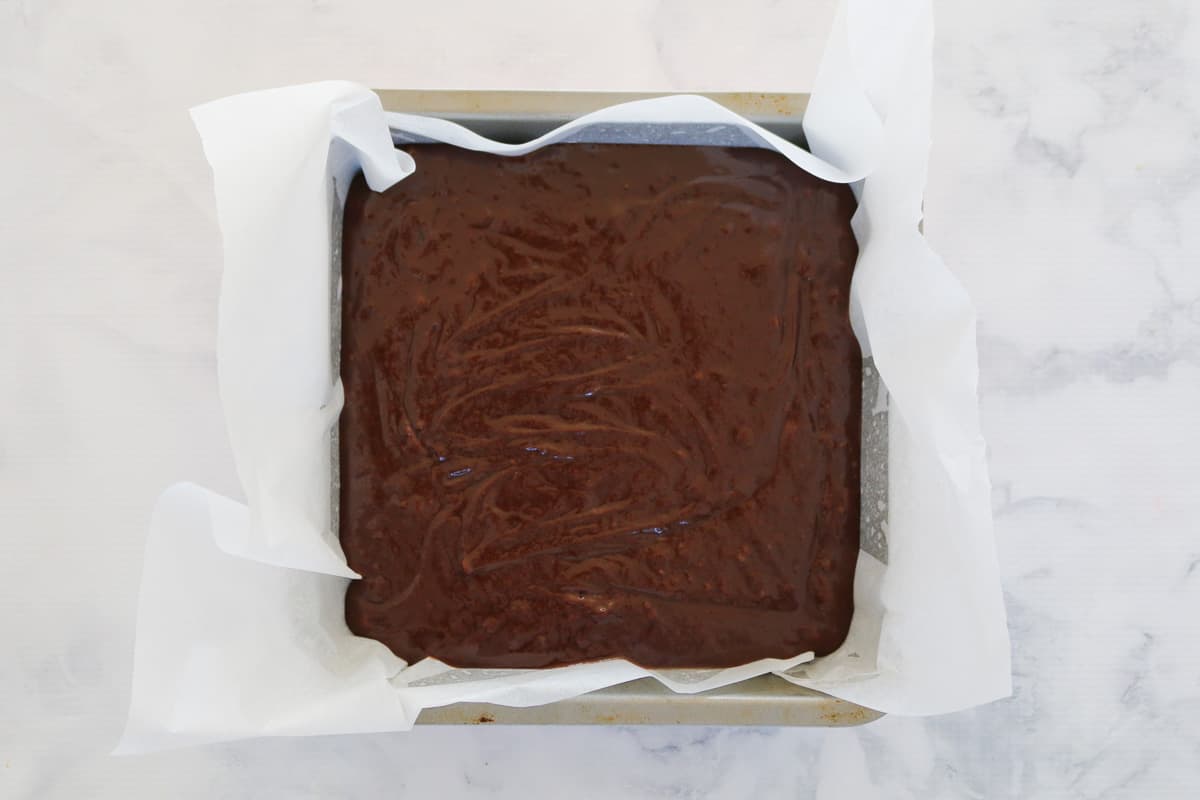 Brownie mixture in a baking paper lined tray.