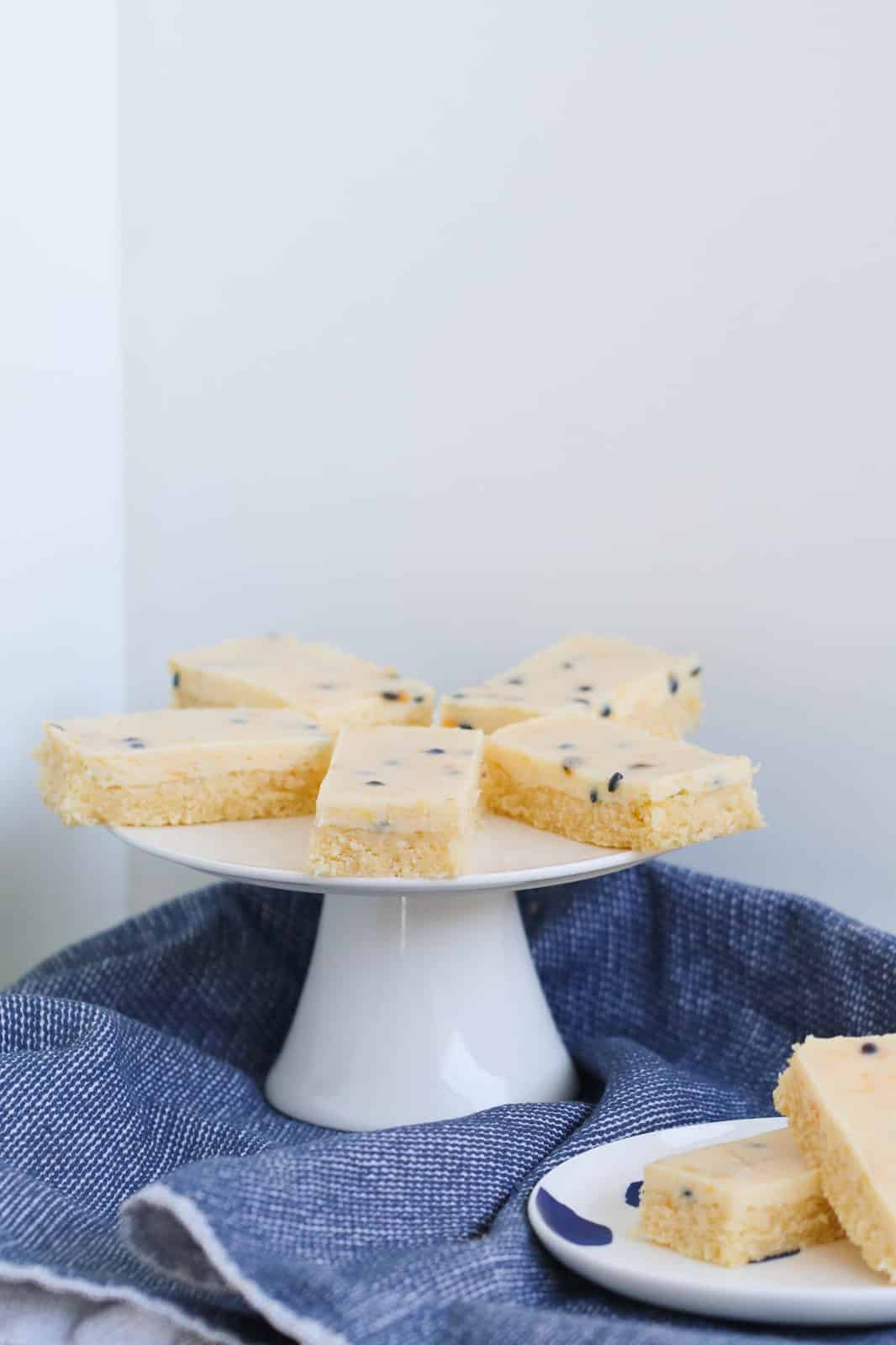 Pieces of baked passionfruit slice on a white cake stand.