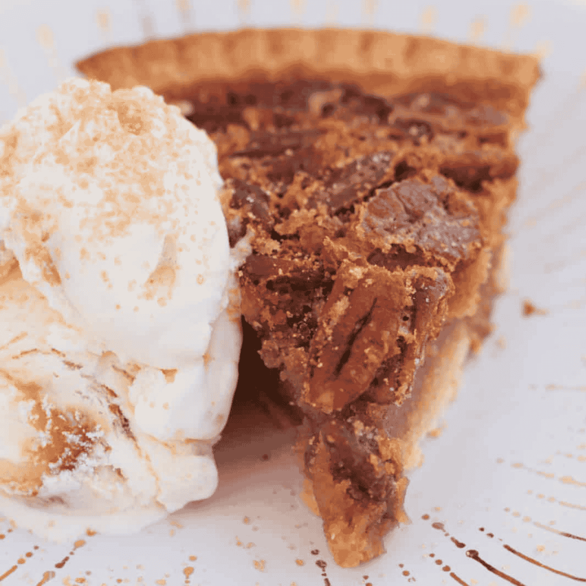 A slice of pecan pie on a plate with a scoop of ice cream.