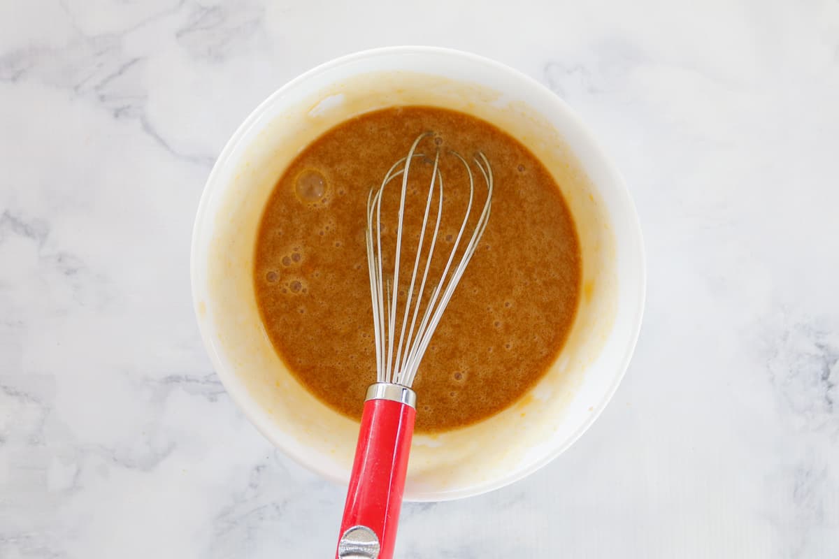 A whisk in a bowl of caramel sauce