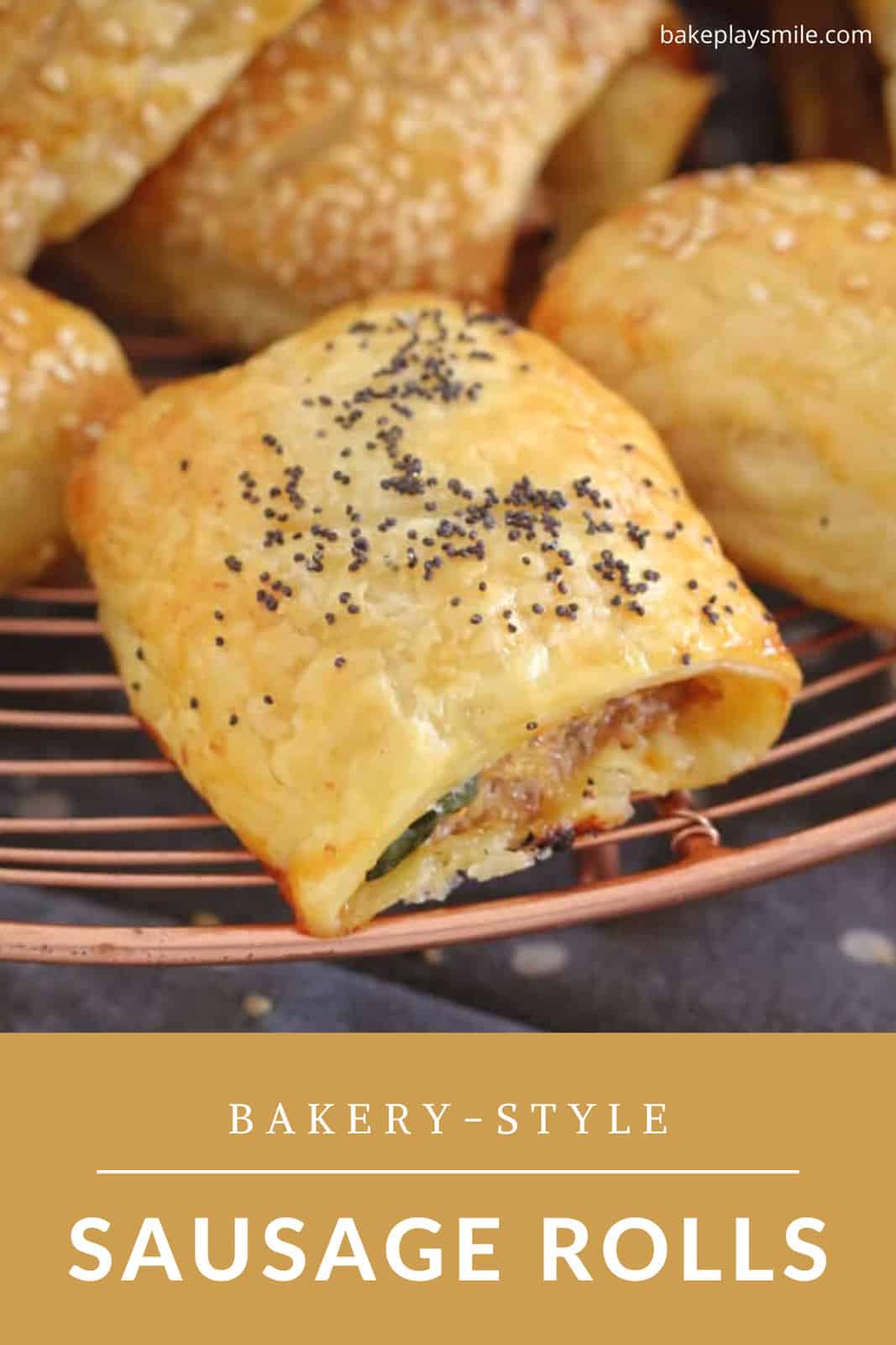 A bunch of golden sausage rolls sprinkled with poppy seeds on a copper wire rack.