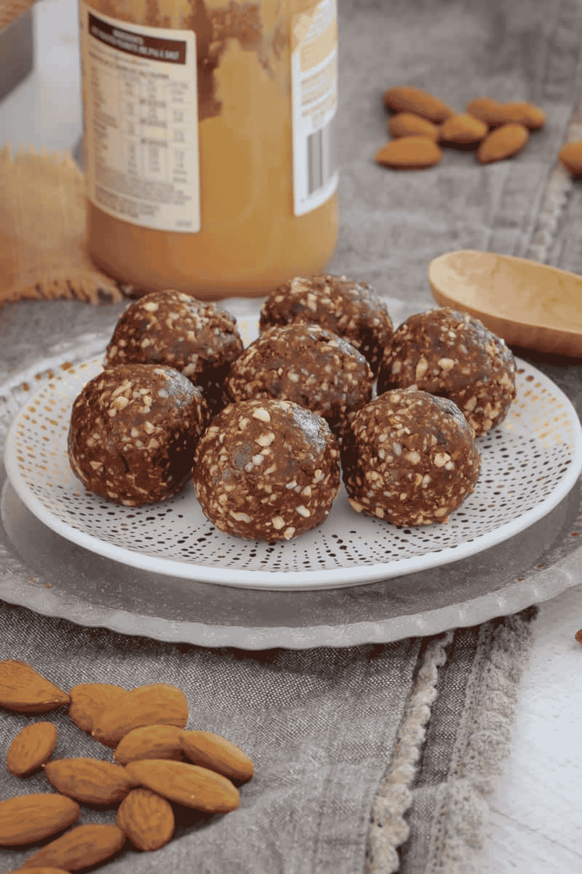A plate of seven round bliss balls with a jar of peanut butter in the background.