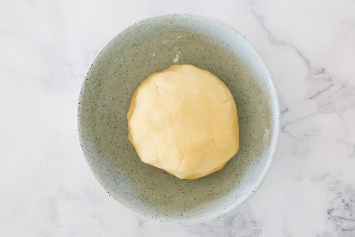 A ball of pastry dough in a green bowl.