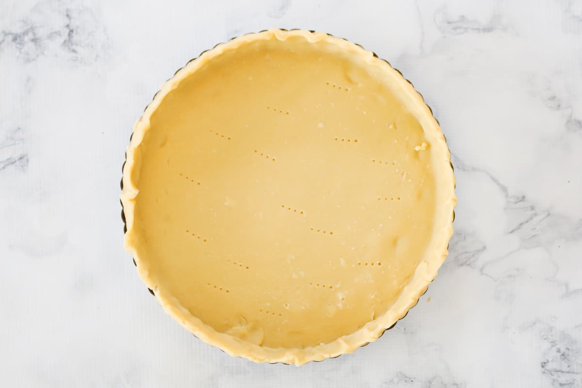 Quiche crust pressed into a round tin.