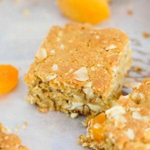 Pieces of oat slice with apricots on baking paper.