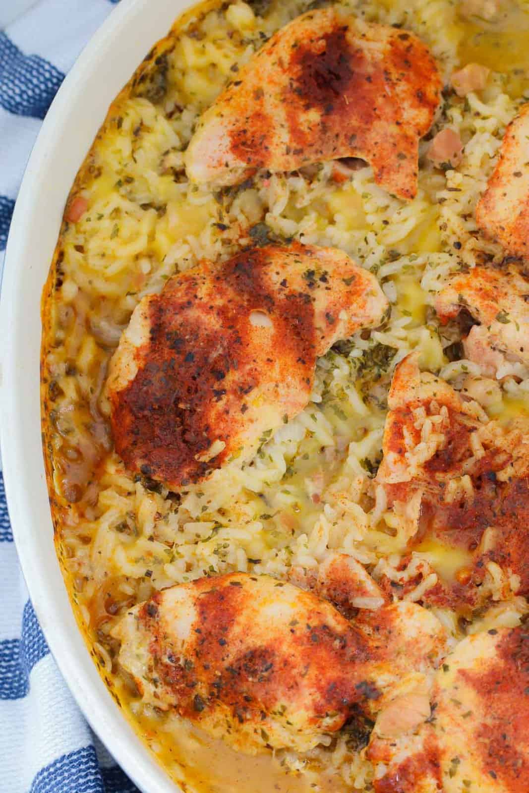 An overhead shot of an oval baking dish filled with baked spicy chicken thighs and creamy rice.
