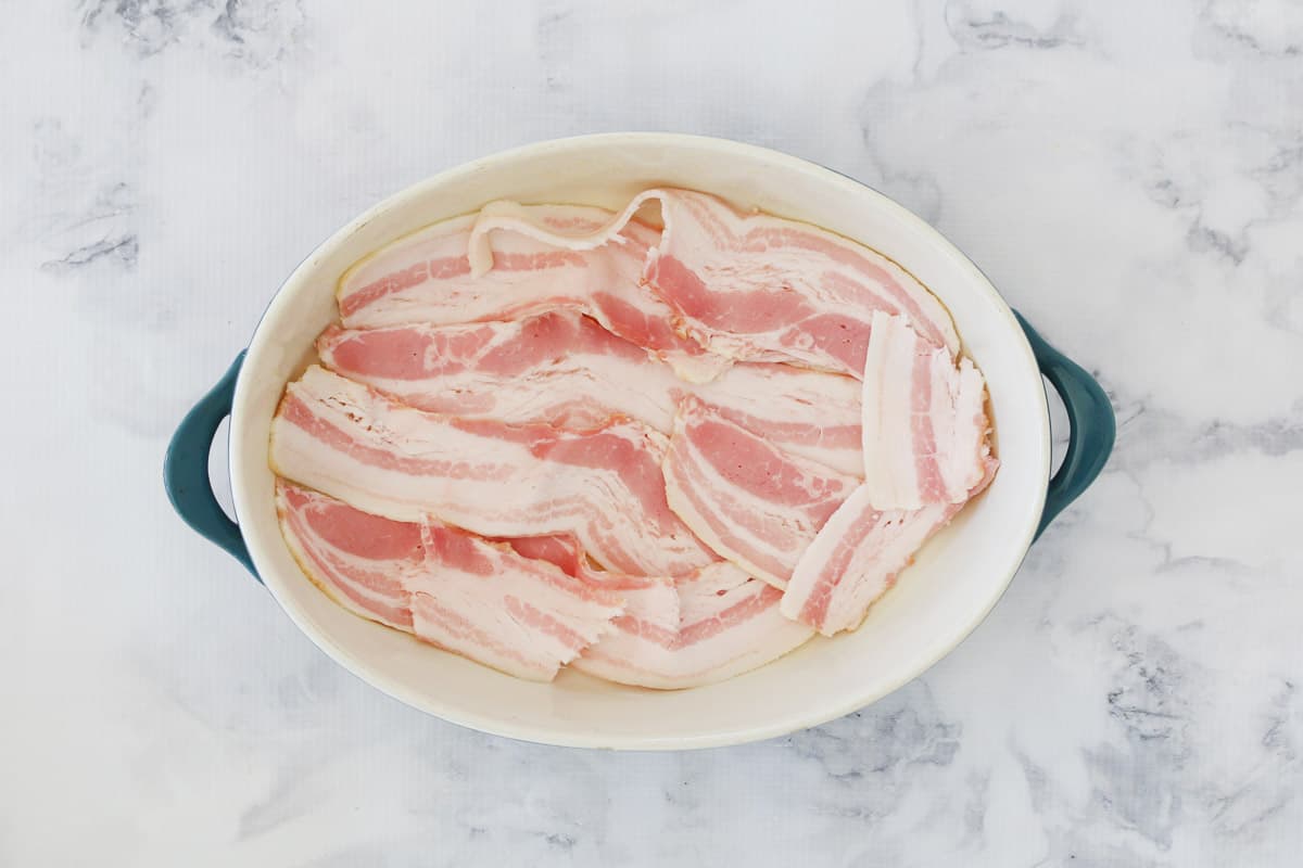 Streaky bacon layered in the base of a casserole dish.
