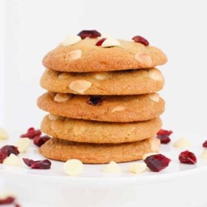 A stack of cookies with white chocolate chips and cranberries.