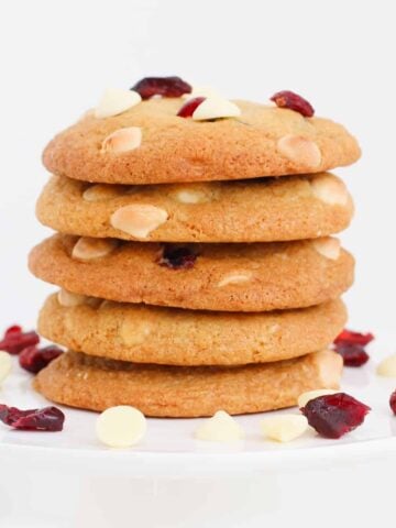 A stack of cookies with white chocolate chips and cranberries.