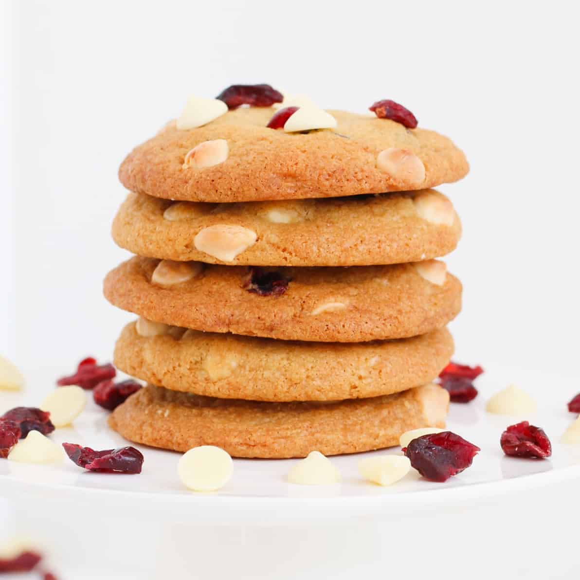 A stack of cookies with white chocolate chips and cranberries.