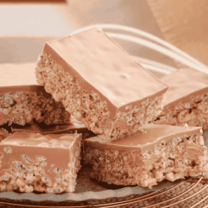 Pieces of Mars Bar slice with chocolate on top stacked together.