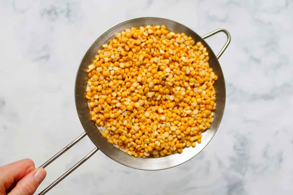 Yellow split peas in a strainer.