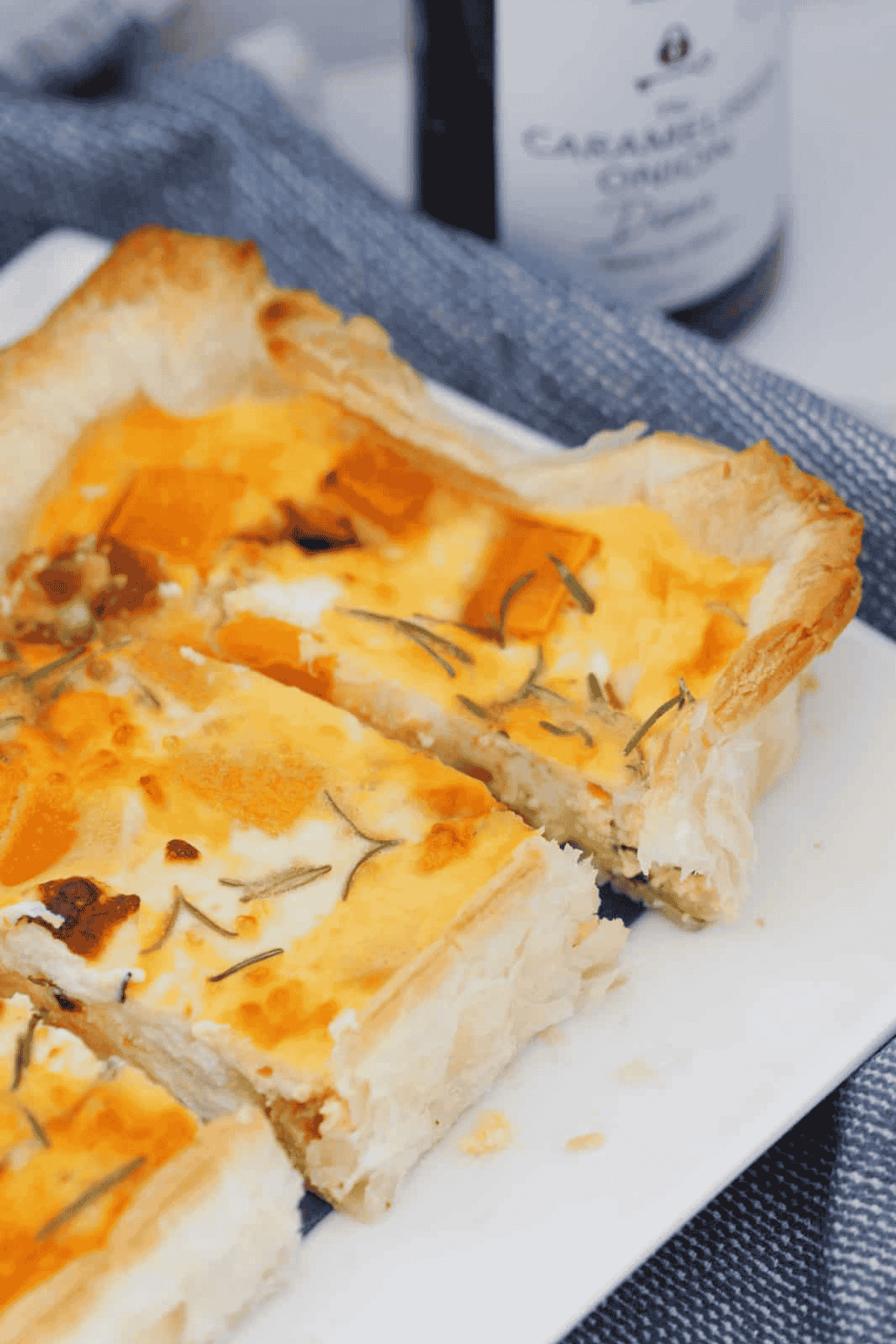A puff pastry tart sliced into pieces showing pumpkin, feta, caramelised onion and rosemary in an egg filling.