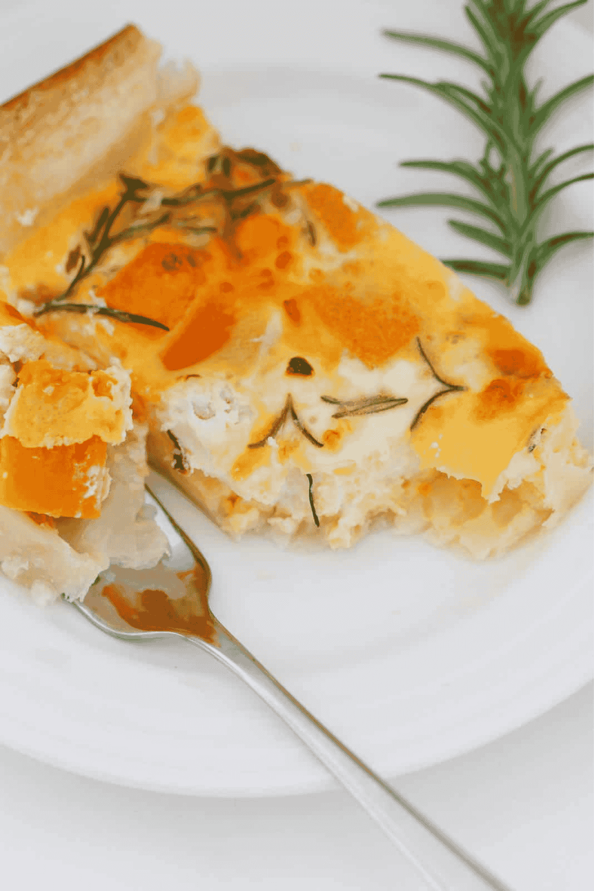 An overhead shot of a puff pastry savoury tart filled with egg, pumpkin, feta and rosemary.