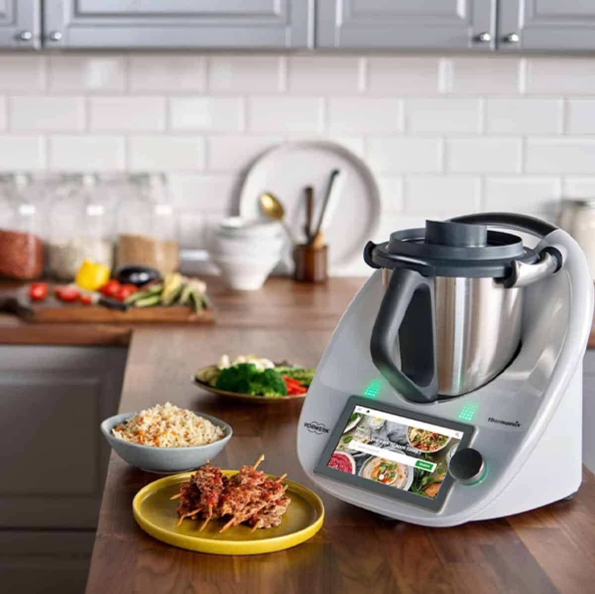 An image of a Thermomix on a kitchen bench surrounded by food.