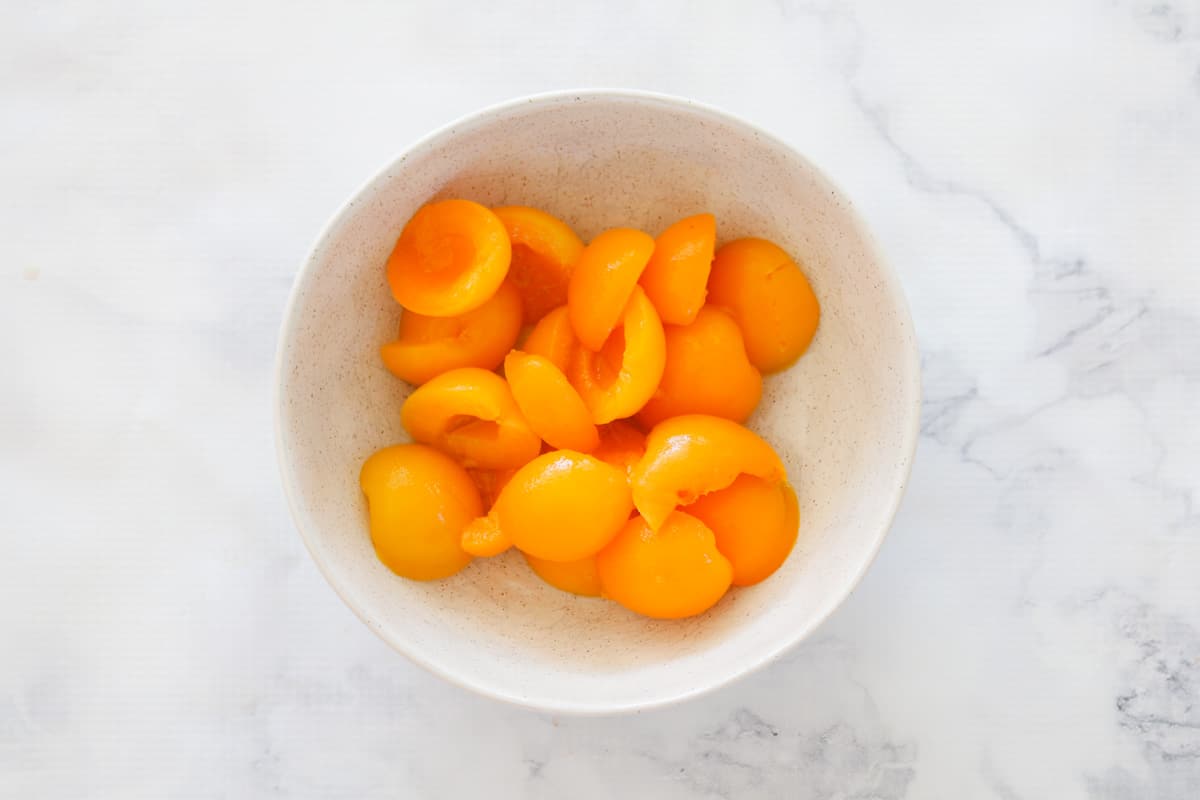 Apricot halves, drained, in a white bowl