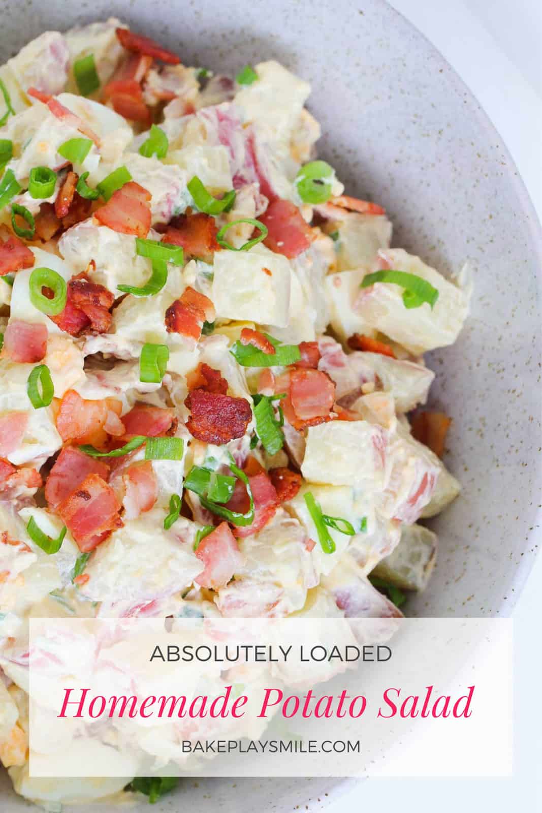 A bowl of potato salad with a creamy dressing, spring onions and bacon.