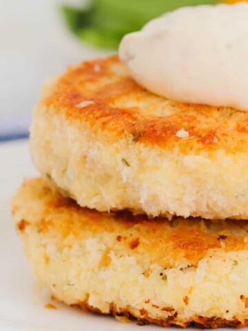 Two golden pan-fried fish cakes on a plate.