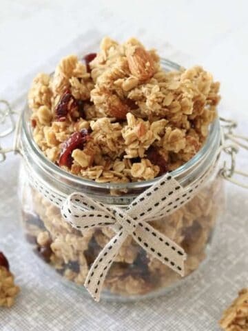 A glass jar filled with fruit and nut granola clusters.