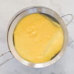 A small sieve filled with homemade lemon curd.