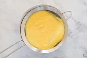 A small sieve filled with homemade lemon curd.