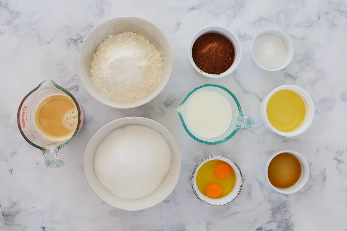 All the ingredients needed for a chocolate mud cake in individual bowls on a bench
