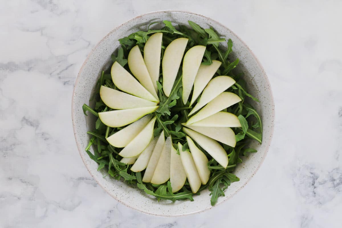 A bowl of rocket and sliced pears.