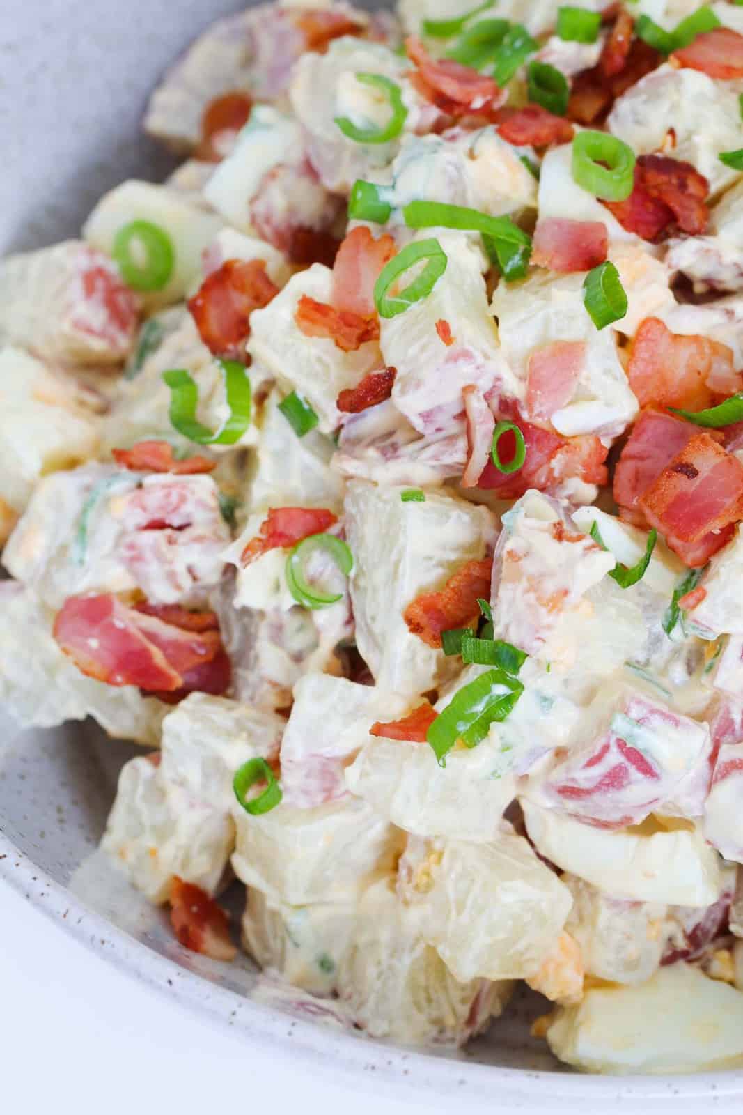A creamy sauce coating potatoes, eggs, spring onions and bacon.