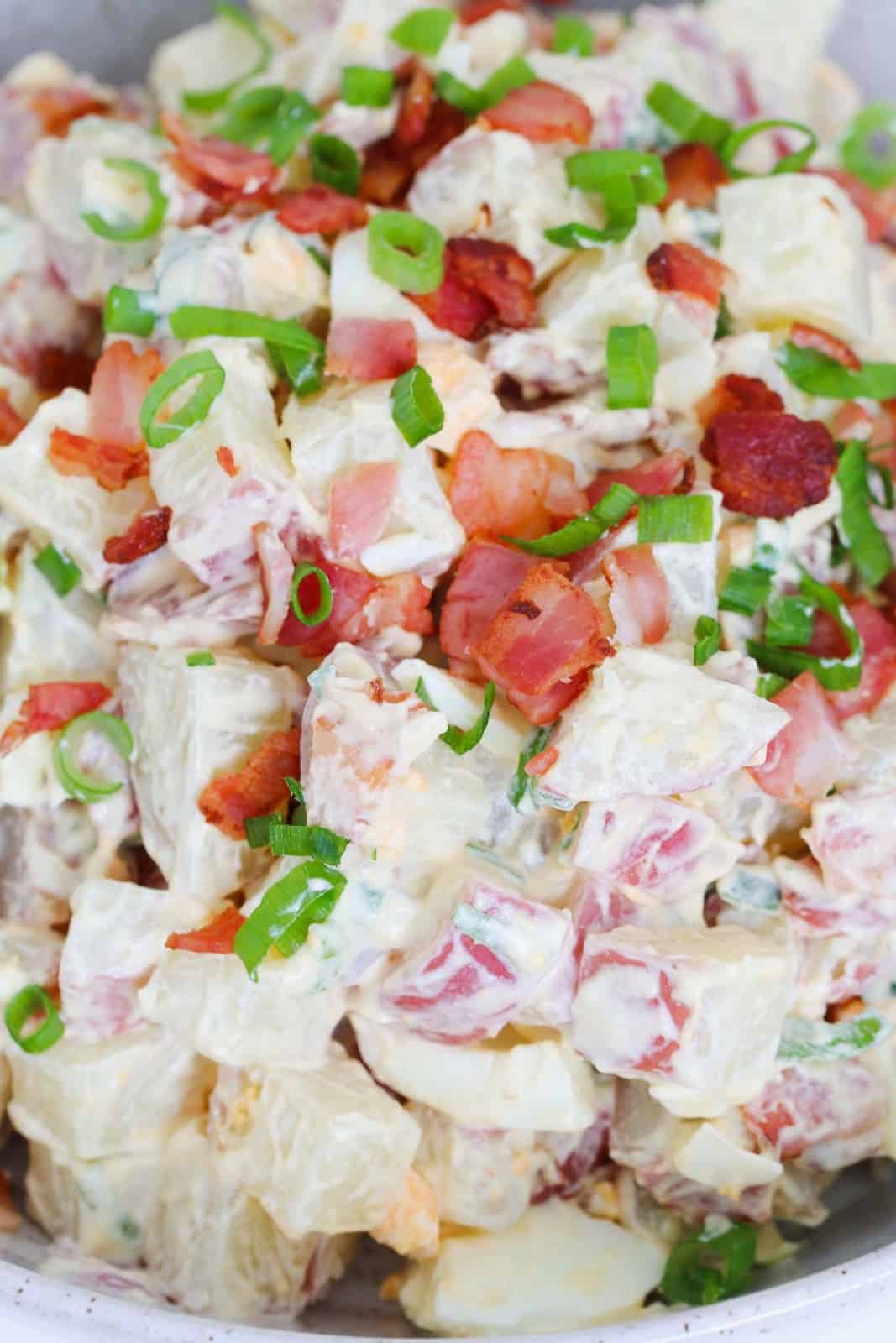 Bacon and spring onions on top of a creamy potato salad.