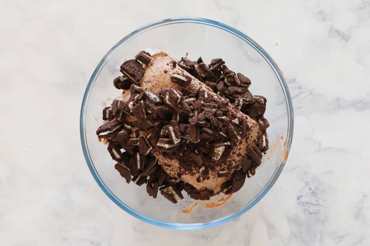 A bowl of chocolate ice-cream with chopped Oreos on top.