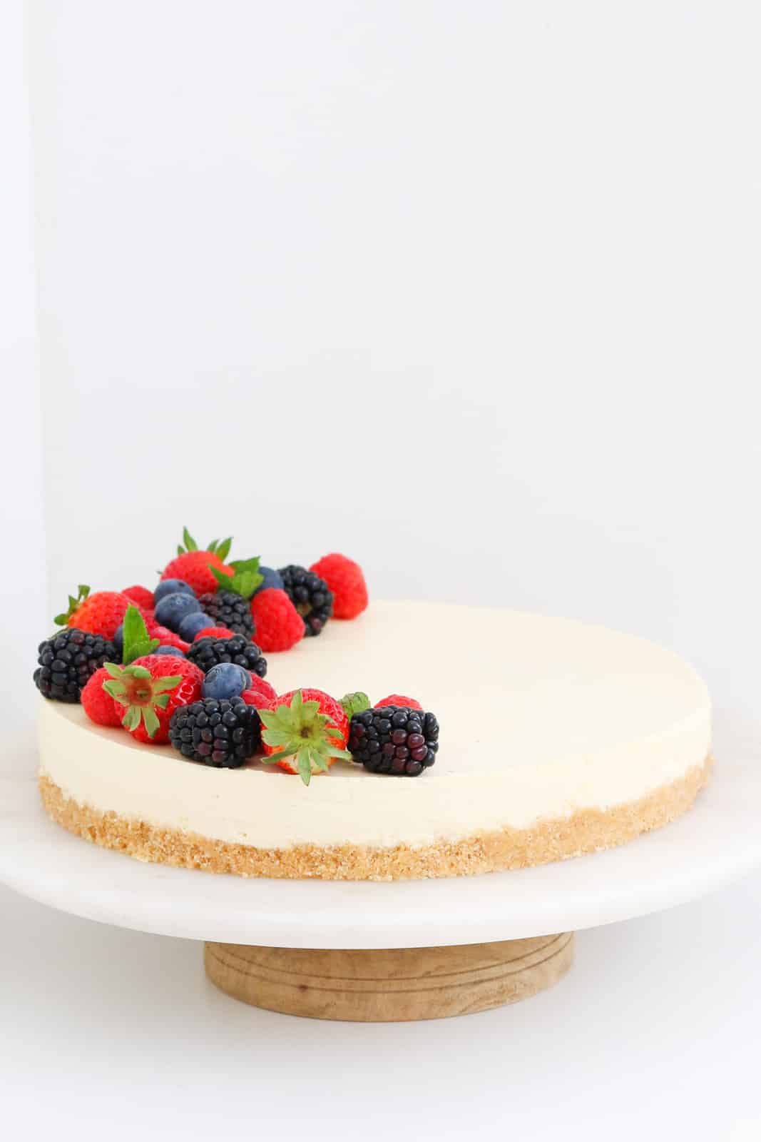 A no bake lemon cheesecake on a cake stand.