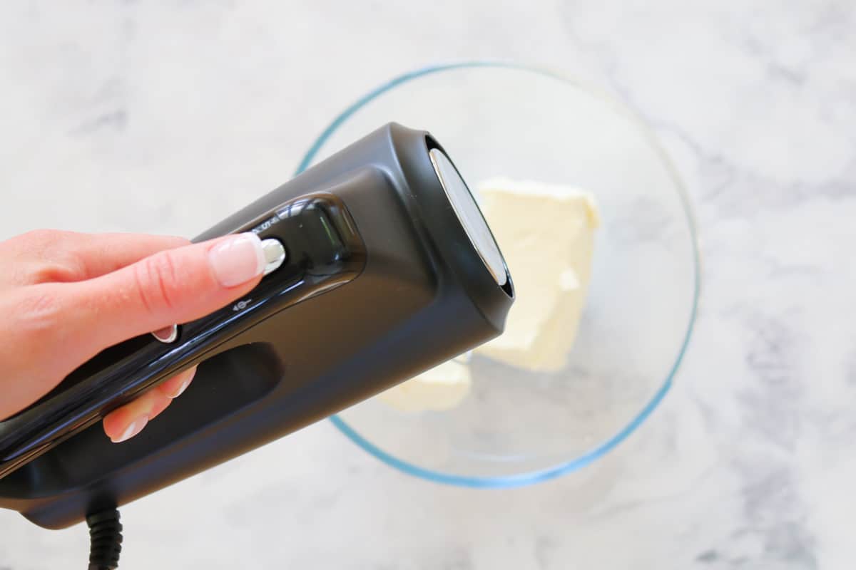 A hand mixer beating cream cheese.