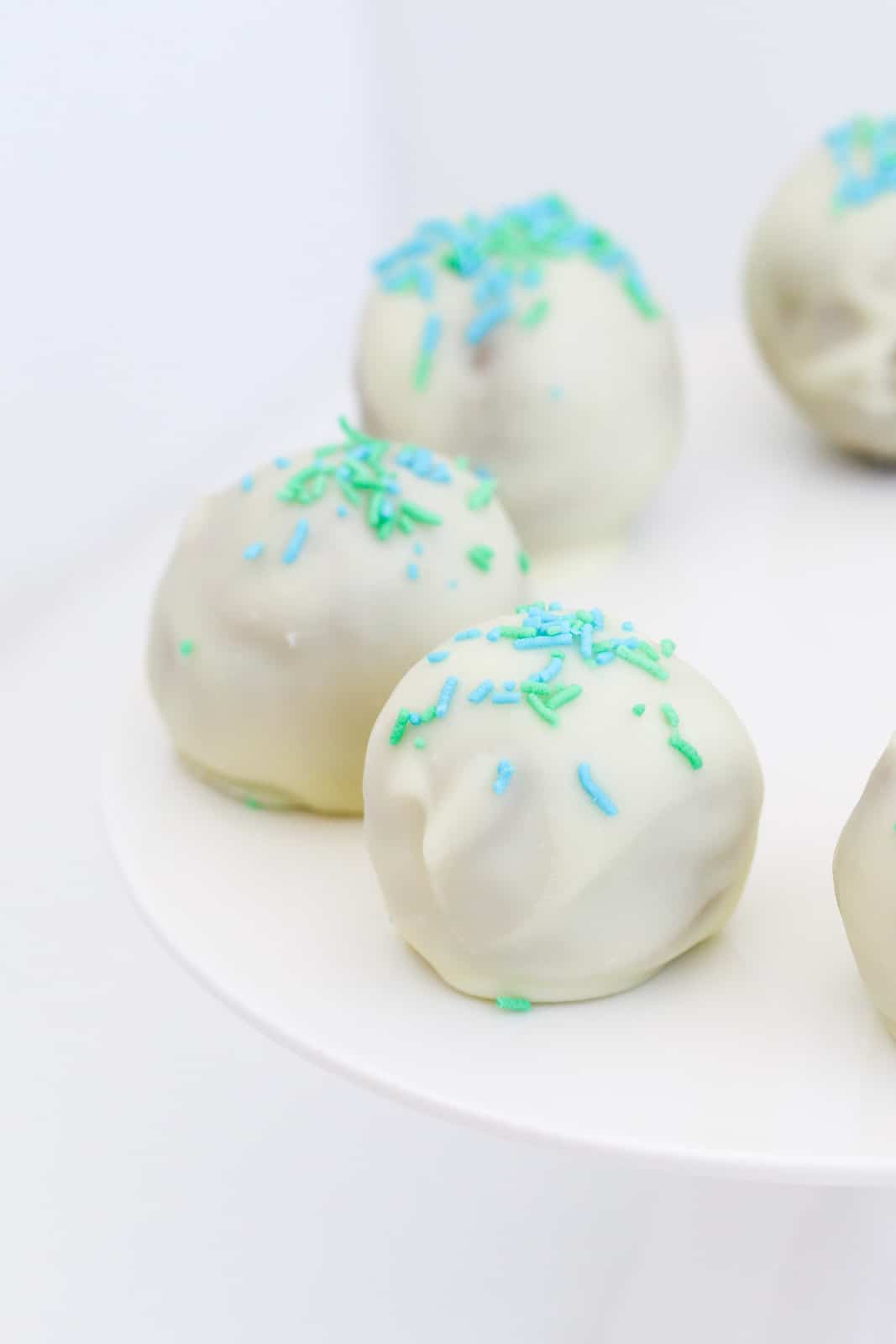 A close up of decorated white chocolate balls on a cake plate.