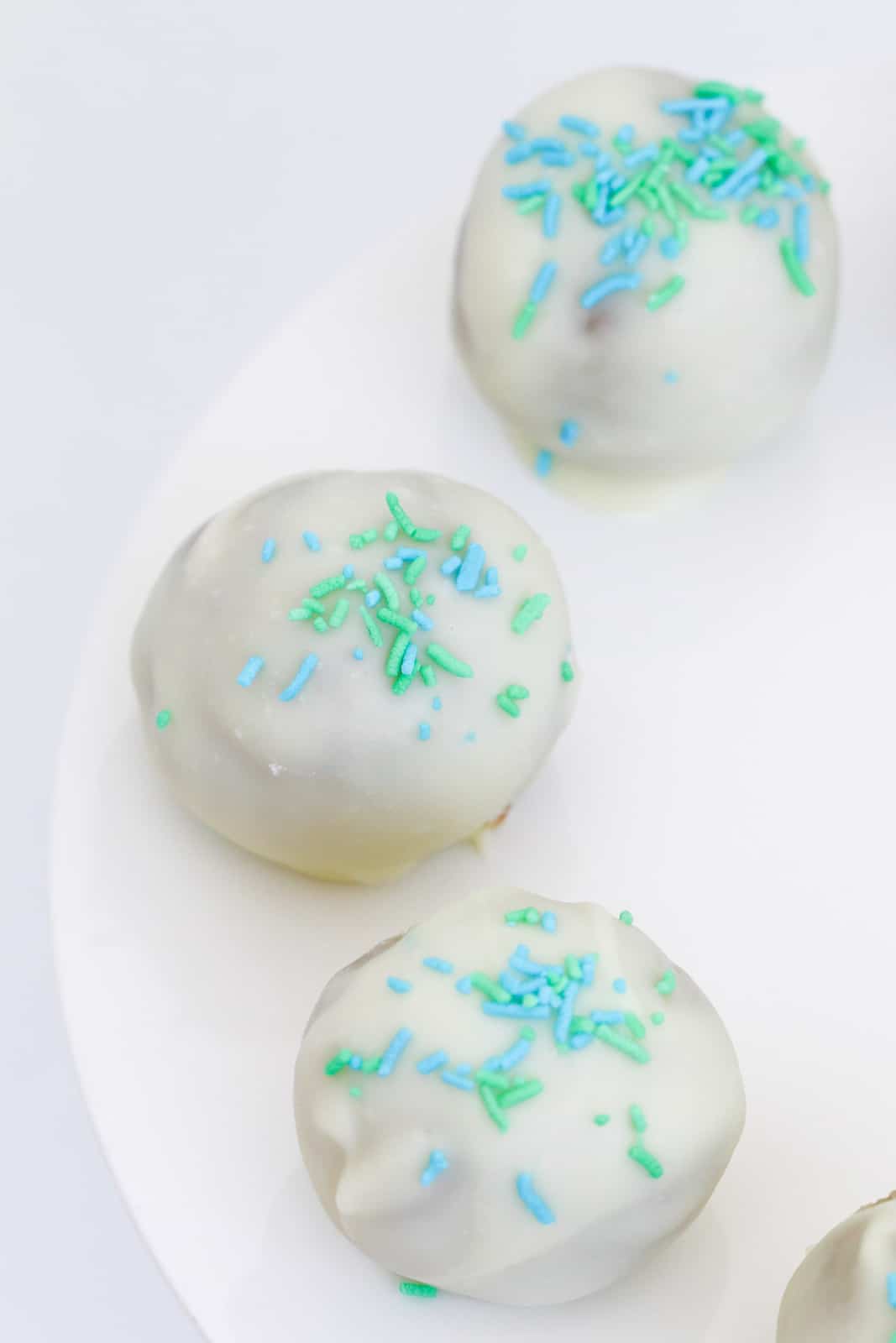 An overhead shot of white chocolate cheesecake balls decorated with sprinkles.