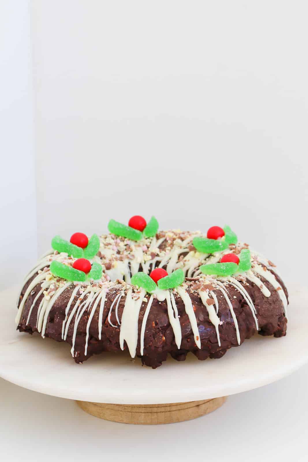 A Christmas themed rocky road chocolate wreath on a cake stand.