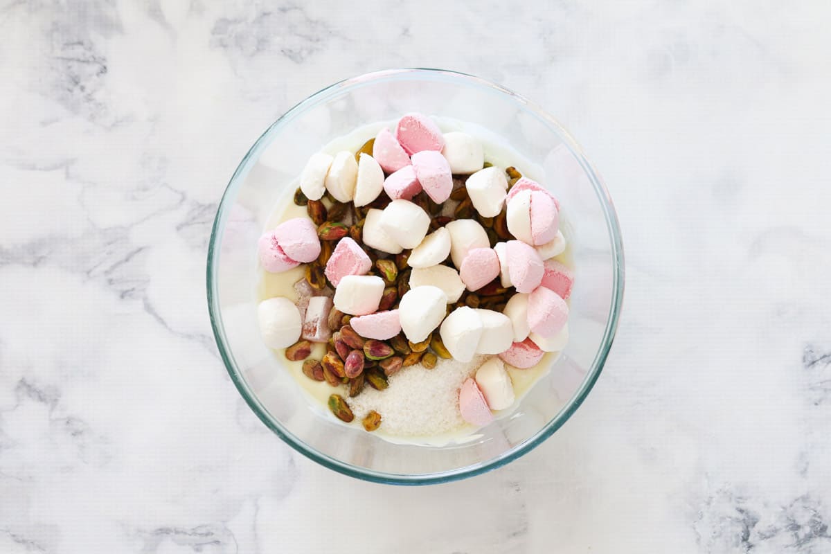 Chopped marshmallows, pistachios and Turkish delight in a bowl on top of melted white chocolate.