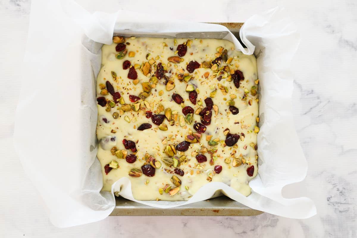 Pistachios and cranberries sprinkled over the top of a white chocolate fudge.